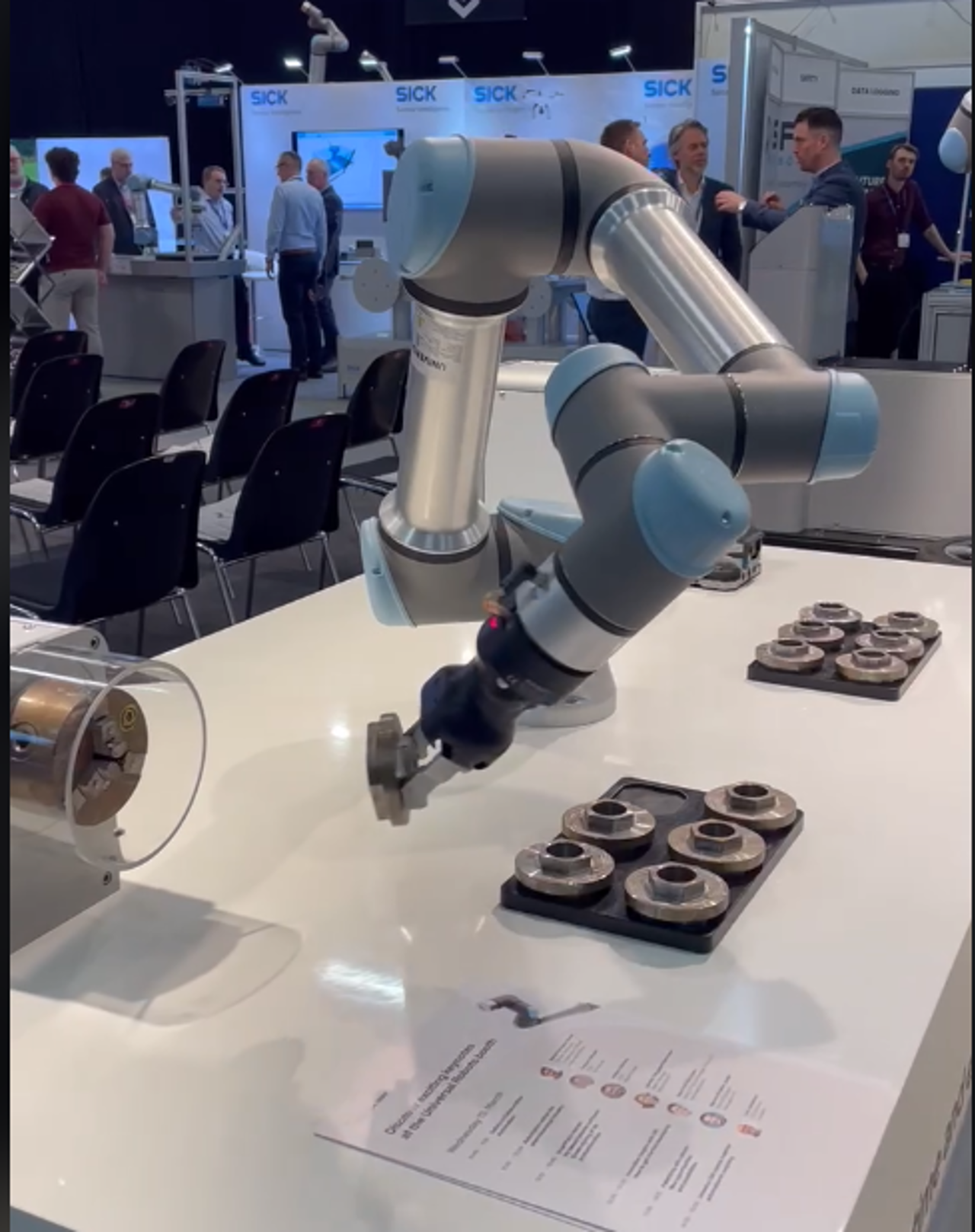 Ein robot frå Universal Robots som flytter ein del fra eit bord til ei maskin.