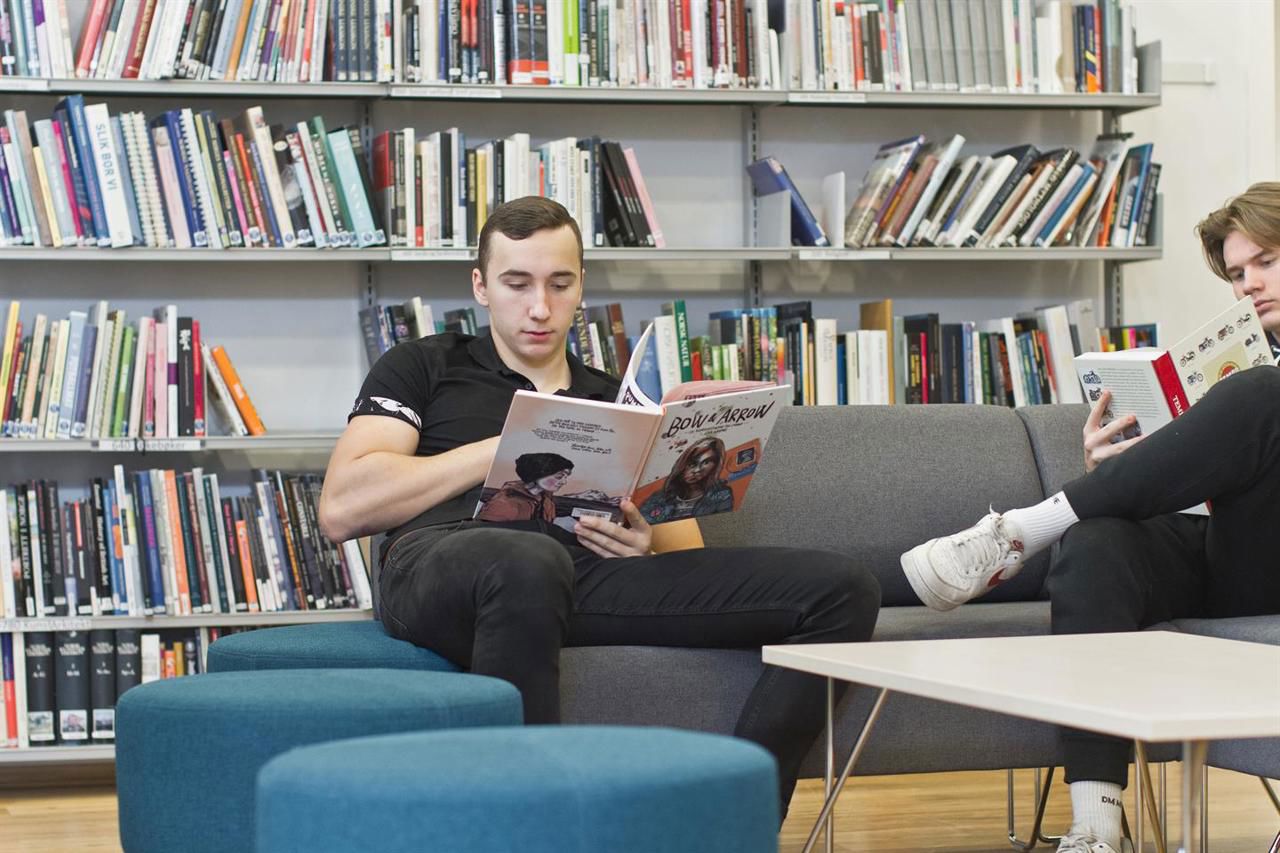 Elevar som sit og les bøker i biblioteket