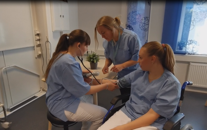 Bilete av to elevar og lærar som øver på praksisrommet