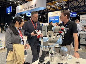 To representantar frå skulen snakkar med ein mann som viser fram robot frå Universal Robots.